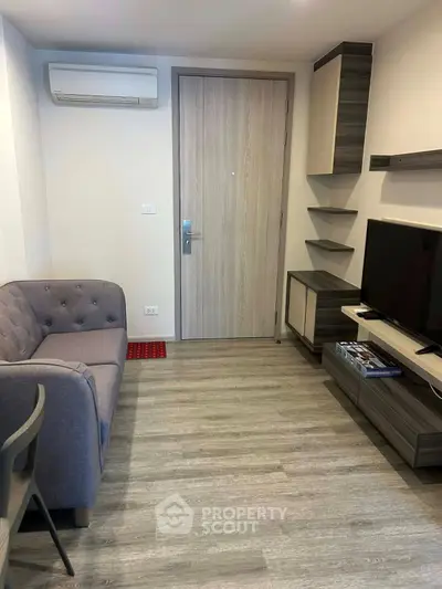 Modern living room with sleek furniture and air conditioning, featuring a cozy sofa and flat-screen TV.