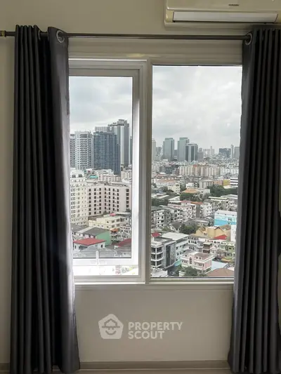 Stunning cityscape view from a high-rise apartment window with modern curtains.
