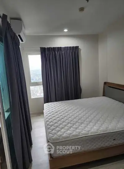 Cozy bedroom with large window and modern furnishings in a high-rise apartment.
