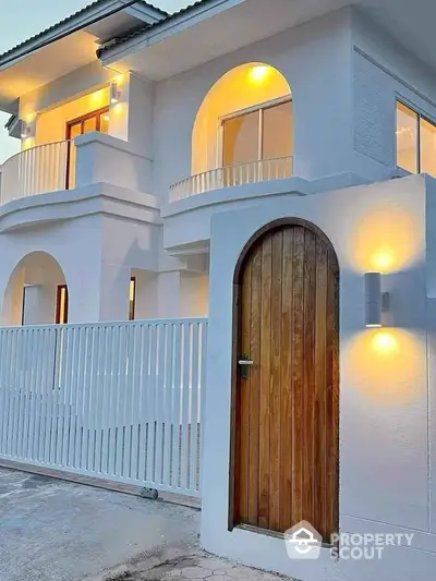 Modern white exterior with elegant wooden door and balcony lighting