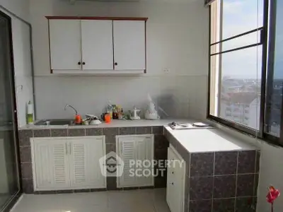 Bright kitchen with closed layout and city view, featuring modern cabinets and ample counter space.