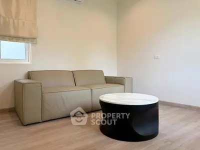 Cozy living room with modern beige sofa and stylish round coffee table on wooden floor.