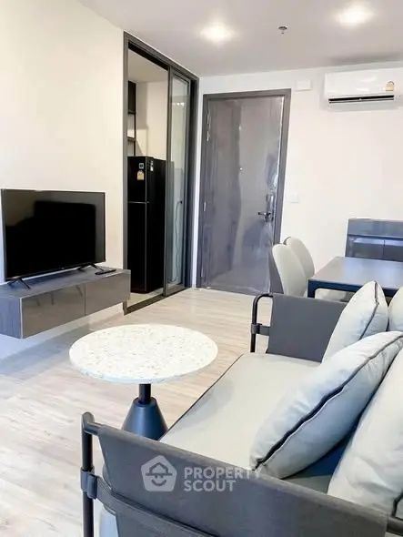 Modern living room with sleek furniture and open layout, featuring a wall-mounted TV and air conditioning.