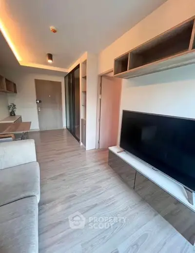 Modern living room with sleek TV setup and stylish wooden flooring.