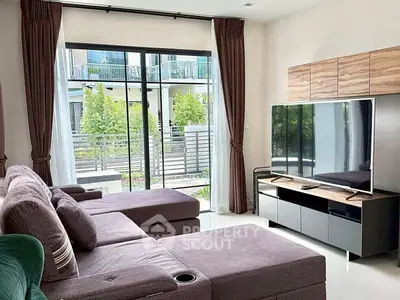 Spacious living room with modern decor and large TV, overlooking a garden view.