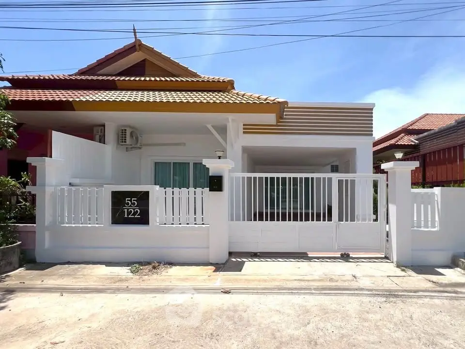Charming single-story house with modern facade and gated entrance in a sunny neighborhood.
