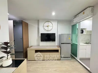 Modern living room with sleek design, featuring a wall-mounted TV and compact kitchen area.