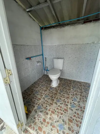 Simple outdoor bathroom with tiled floor and basic fixtures.