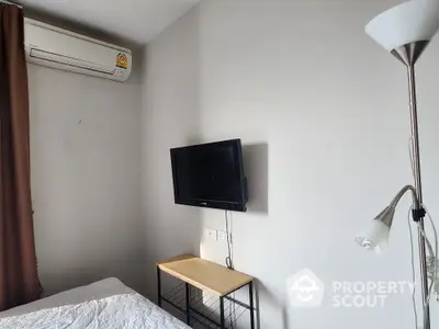 Cozy bedroom with wall-mounted TV and air conditioning unit, perfect for relaxation.