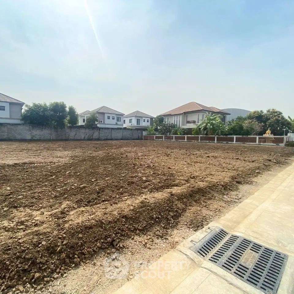 Prime residential land for sale in a serene neighborhood with modern homes and clear skies.