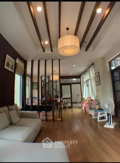Spacious living room with modern decor and wooden flooring, ideal for family gatherings.
