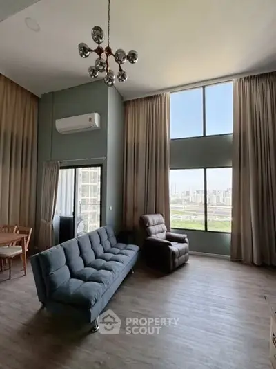 Spacious living room with modern furniture and large windows offering city views.