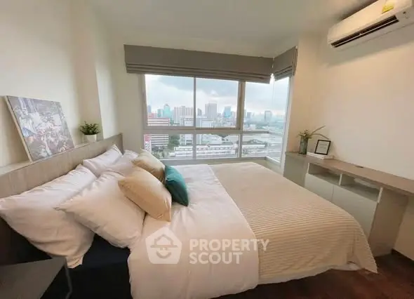 Cozy bedroom with city view and modern decor in high-rise apartment.