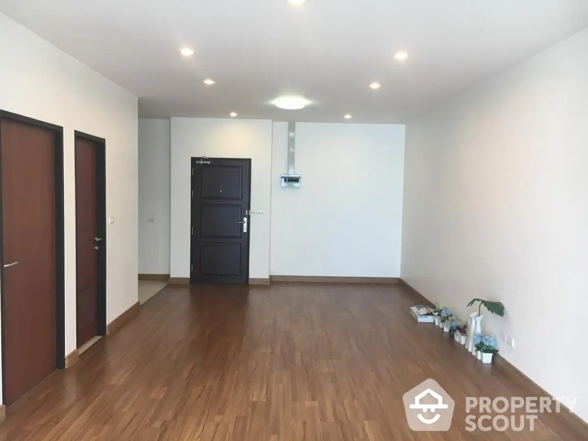 Spacious empty living room with wooden flooring and recessed lighting, ideal for customization.