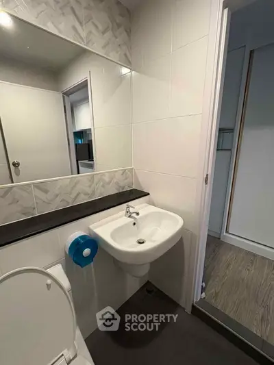 Modern bathroom with sleek sink and large mirror in contemporary apartment.