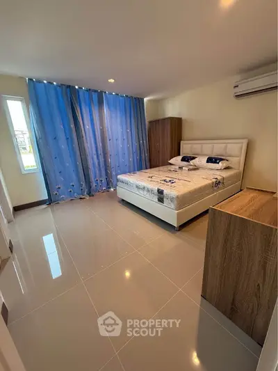 Spacious bedroom with modern decor and large window for natural light.