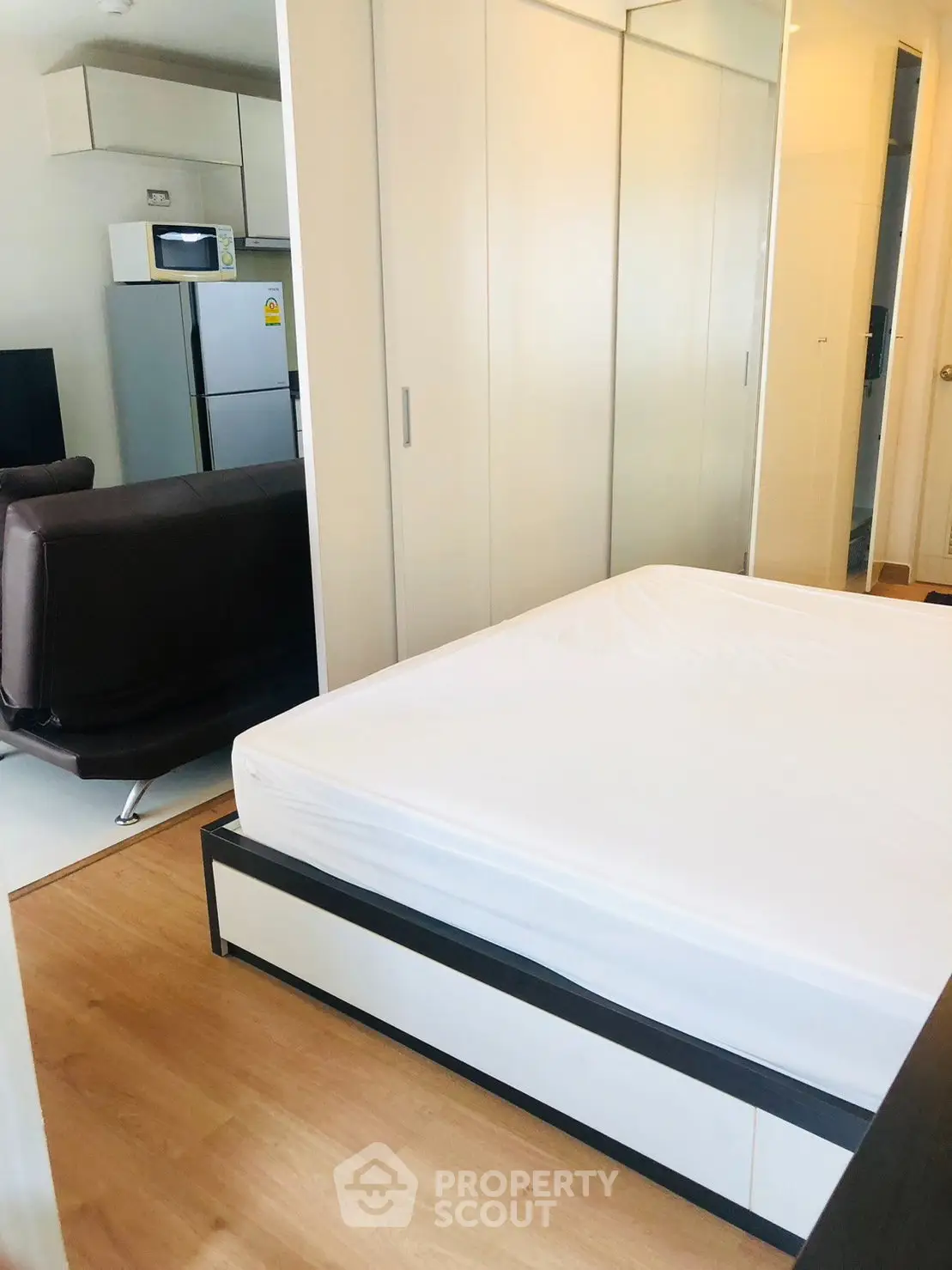 Modern studio apartment with open layout, featuring a cozy bed, sleek kitchen, and stylish living area.