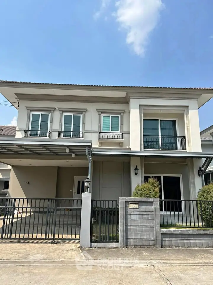 Modern two-story house with balcony and gated entrance in a suburban neighborhood.