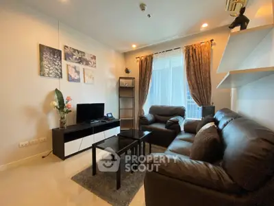 Cozy living room with modern decor, leather sofas, and natural light from large window.
