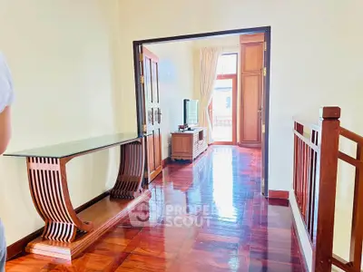 Elegant hallway with polished wooden floors and stylish furniture leading to a bright living area.