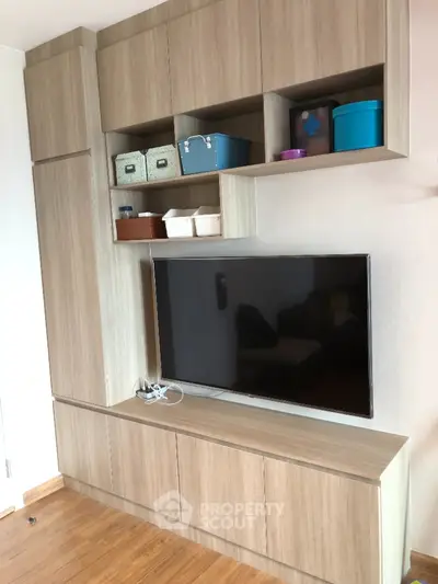 Modern living room with stylish wooden TV cabinet and storage shelves.