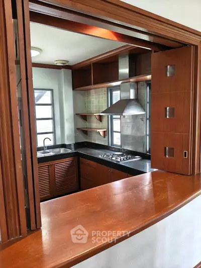 Charming kitchen with open layout and modern gas stove, featuring elegant wooden cabinetry and ample natural light.