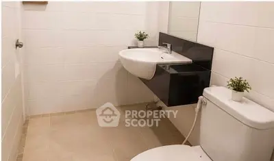 Modern bathroom with sleek fixtures and minimalist design, featuring a wall-mounted sink and toilet.