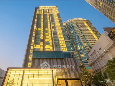 Stunning modern high-rise building with illuminated windows against a clear blue sky, showcasing urban luxury.