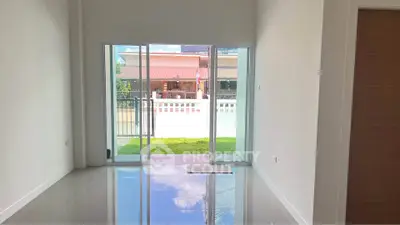 Spacious living room with large glass doors opening to a lush garden view.