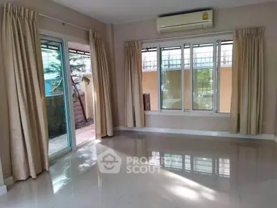 Spacious living room with large windows and sliding glass door leading to outdoor area.