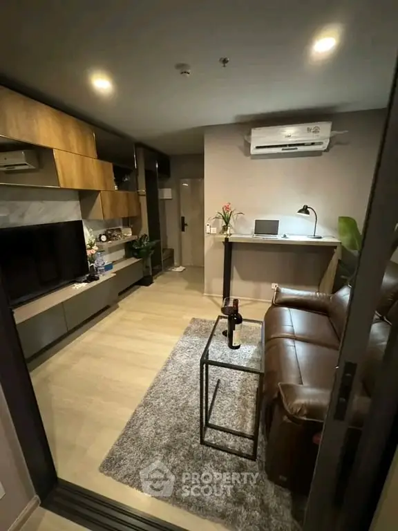 Modern living room with leather sofa, wall-mounted TV, and stylish decor in a cozy apartment.