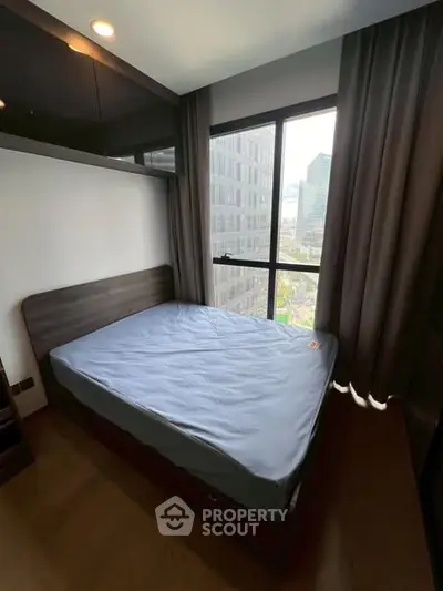 Modern bedroom with large window offering city view, featuring sleek design and ample natural light.