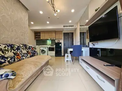 Modern living room with open kitchen, featuring floral sofa and wall-mounted TV, ideal for cozy urban living.