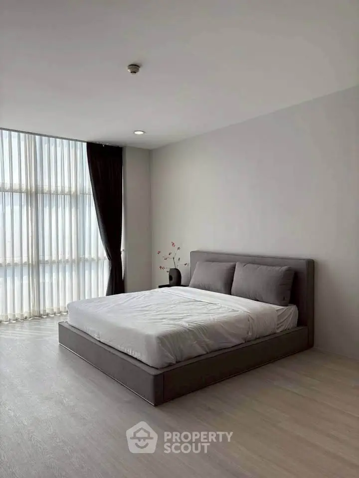 Spacious modern bedroom with large window and minimalist decor