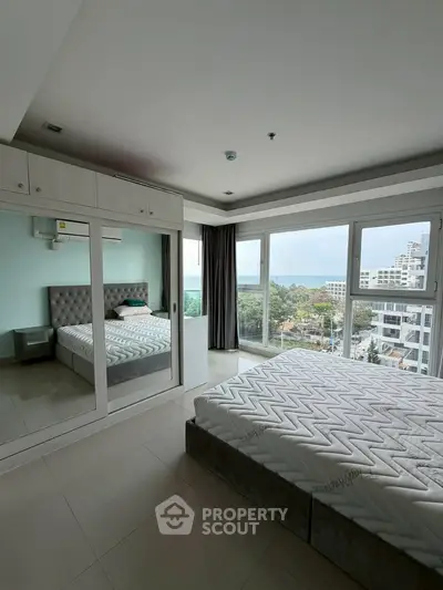 Spacious bedroom with large windows offering stunning city and sea views.