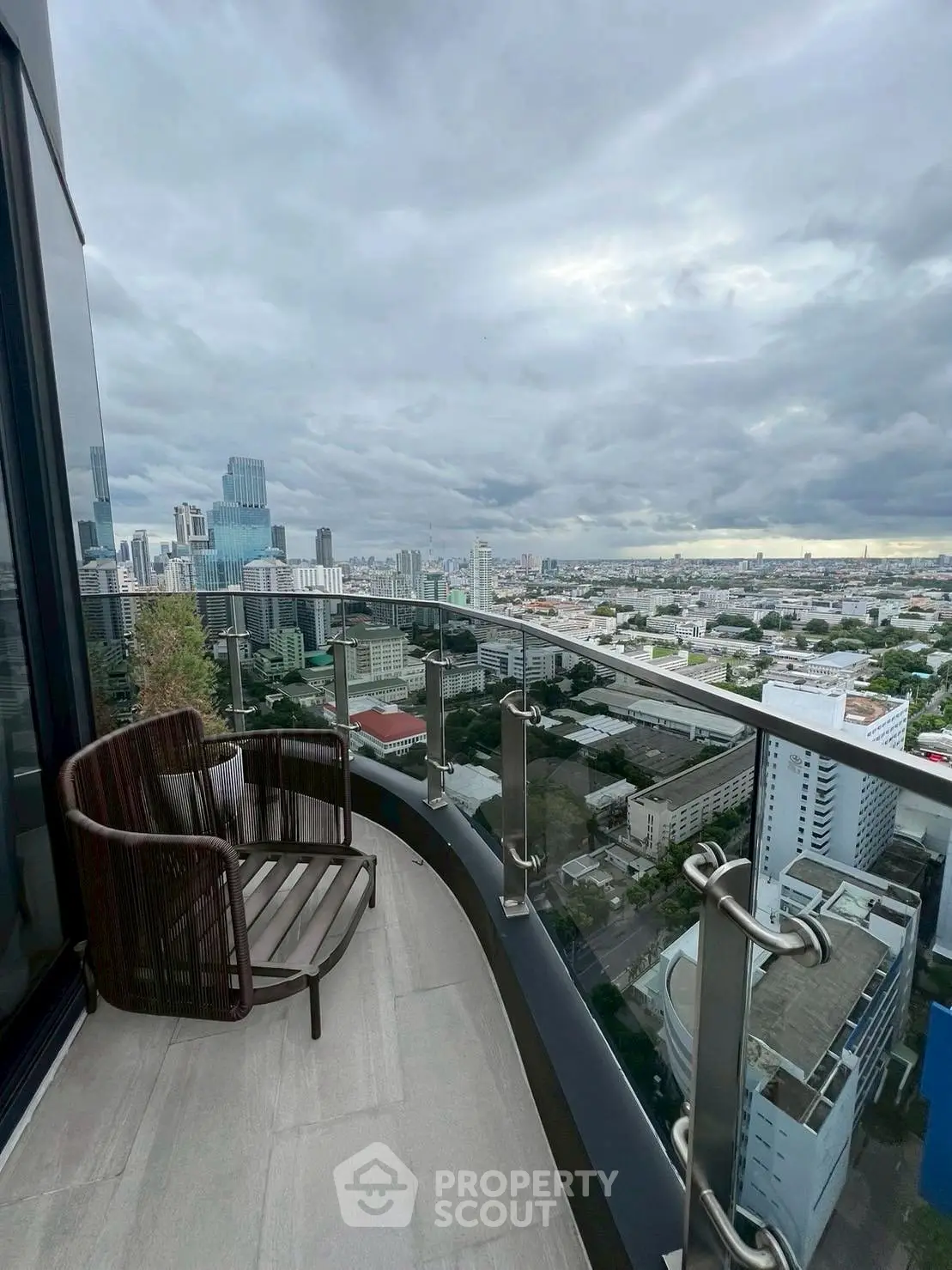 Stunning cityscape view from a modern high-rise balcony with sleek glass railing.