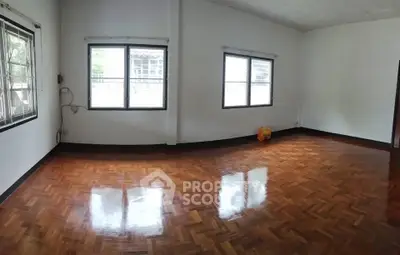 Spacious empty room with polished wooden floors and large windows