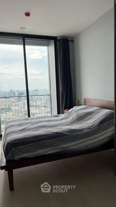 Modern bedroom with city view and large windows in high-rise apartment