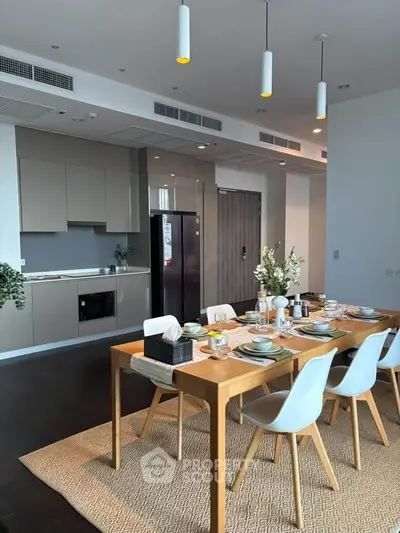 Modern dining area with elegant table setting and sleek kitchen in open layout apartment.