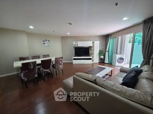 Spacious living room with dining area and large TV, featuring modern furniture and natural light.