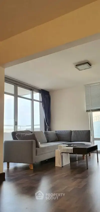 Spacious living room with modern gray sofa and large windows offering ample natural light.