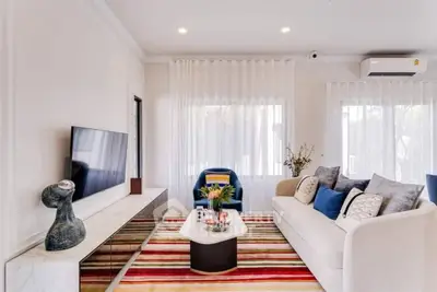 Modern living room with stylish decor and large TV, featuring a colorful striped rug and elegant furniture.