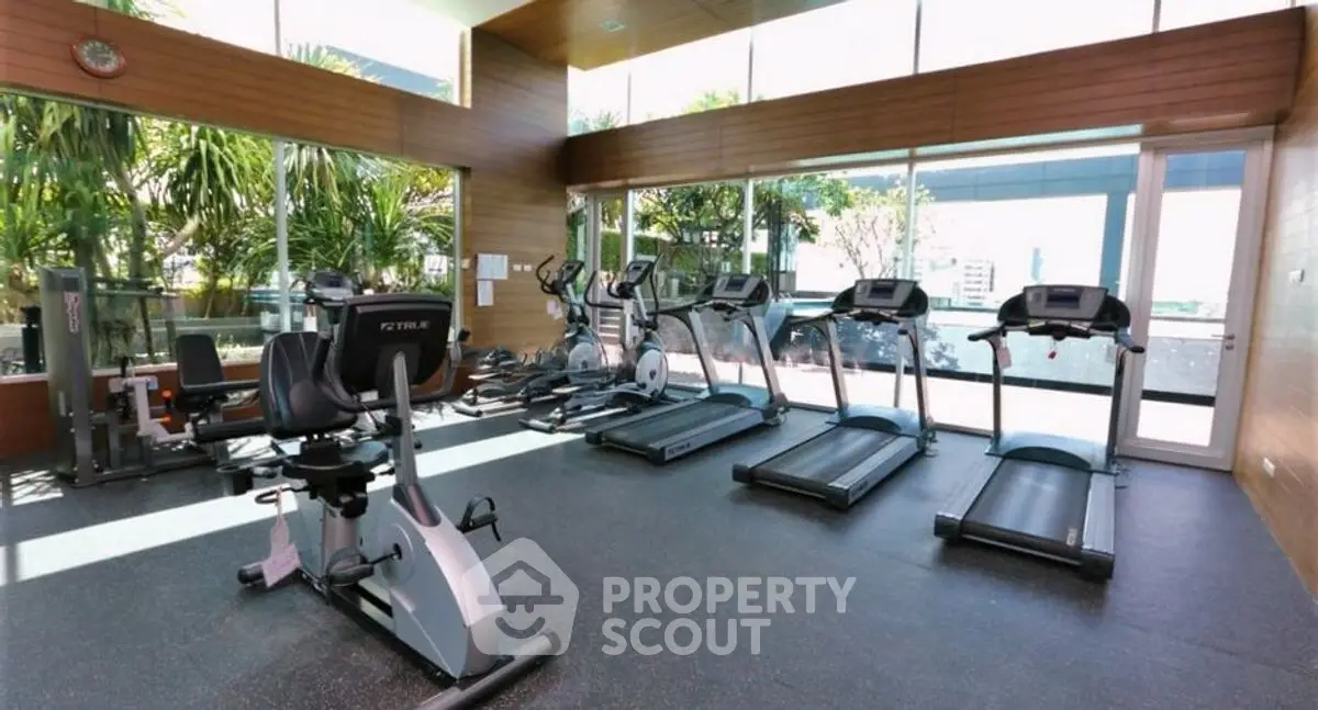 Spacious modern gym with state-of-the-art equipment and large windows offering natural light.