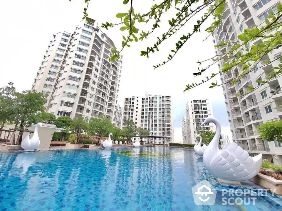 Luxurious apartment complex with stunning pool and swan sculptures, ideal for modern living.