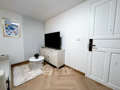 Modern living room with stylish decor and flat-screen TV, featuring a cozy white sofa and chic wooden flooring.