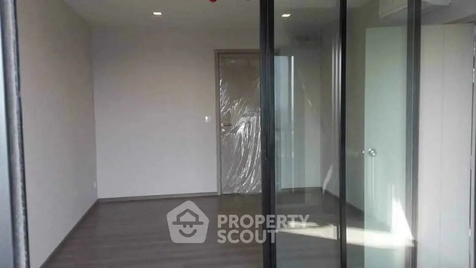 Spacious empty room with sliding glass doors and modern flooring, ideal for customization.