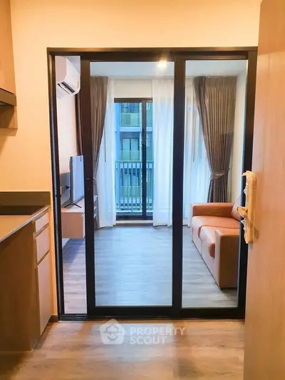 Modern apartment with sliding glass doors leading to a cozy living room and balcony view.