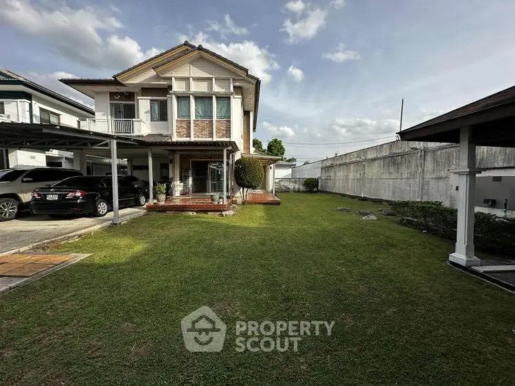 Charming two-story house with spacious green lawn and carport in suburban setting.