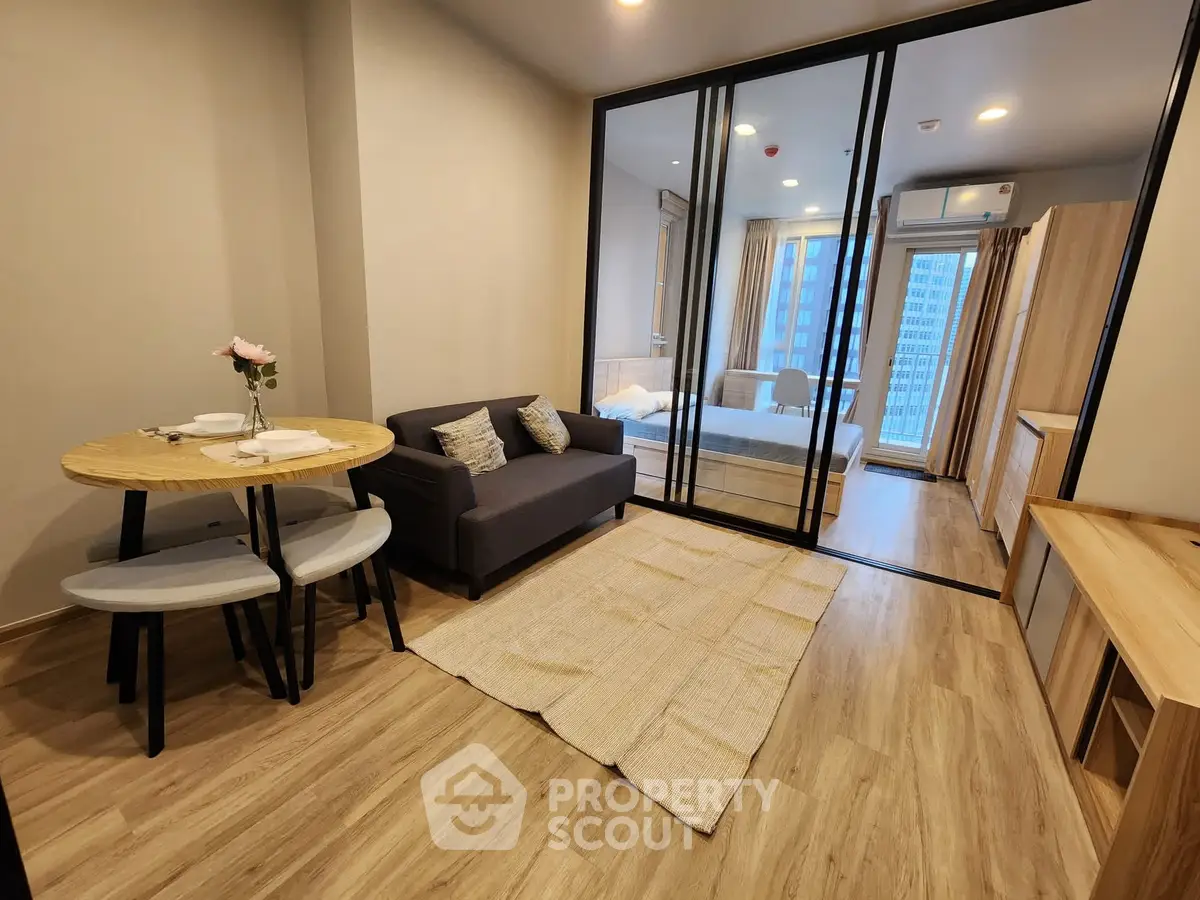 Modern apartment with open living room and bedroom, featuring stylish furniture and large windows.