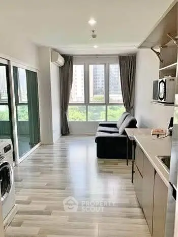 Modern open-plan living room with kitchen and large windows offering city views.